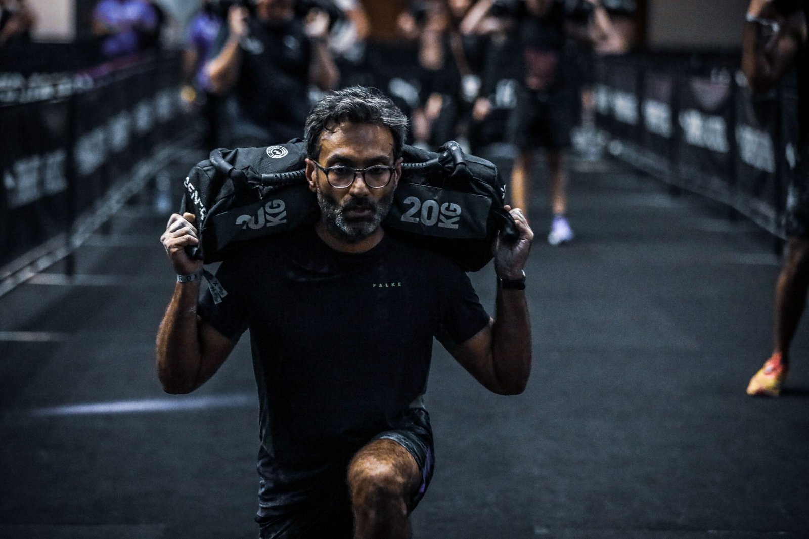 Man performing intense sandbag lunges during Momentum Method fitness training.